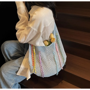 Detail of light blue crochet tote bag featuring colorful tassels and woven textures