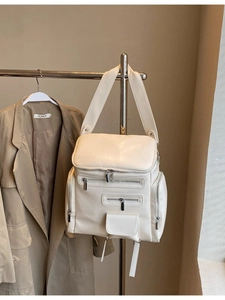 Minimalist beige multi-pocket faux leather backpack with metallic zippers on a hanger