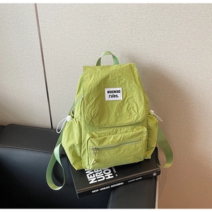 Dettaglio dello zaino in nylon verde avocado con patta e tasca frontale con cerniera