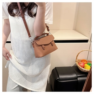 Detailed close-up of a brown woven crossbody bag with dual button decor and top handle