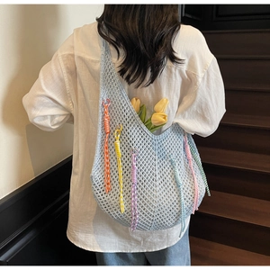 Detail of light blue knit tote bag with colorful tassels on a wooden staircase
