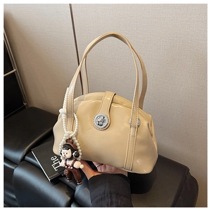Détail d'un sac bowling en cuir verni beige avec fermoir argenté et porte-clé poupée