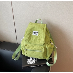 Dettaglio dello zaino in nylon verde con tasca frontale zip e tasca laterale a cordoncino