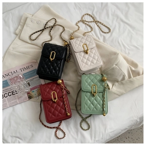 Flat lay of four quilted chain mini crossbody bags in black, beige, red and green