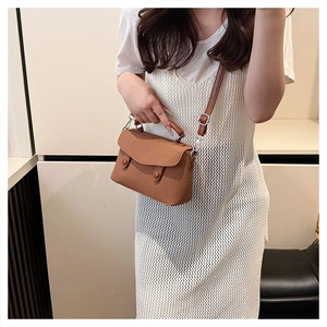 Brown canvas crossbody bag with decorative buttons shown on a white summer dress