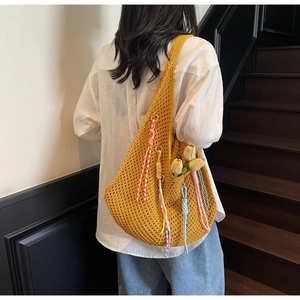 Detail of yellow knit tote bag with colorful tassels and spacious interior for summer