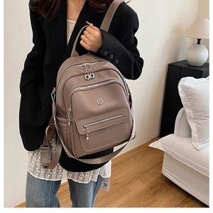 Detail view of the textured leather backpack with silver zippers and multi-pocket design