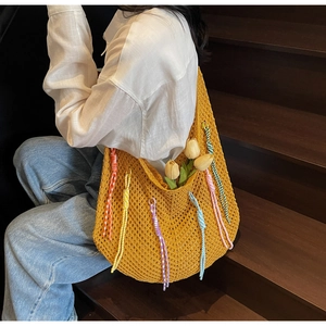 Detail view of ginger yellow hollow knit tote bag with colorful fringe on casual outfit