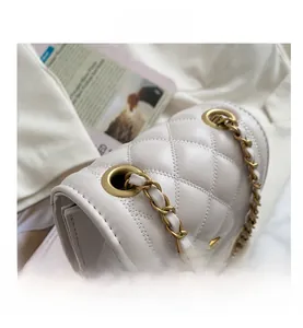 Detailed macro view of white quilted leather texture and matte gold metal chain eyelets