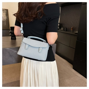 Model wearing light blue textured mini square bag with dual buckles and shoulder strap
