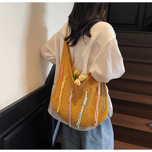 Detail of hollow knit yellow beach tote featuring colorful braided tassels and tulip decor