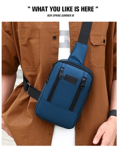 Detail of blue crossbody bag featuring adjustable wide strap and vertical zipper pocket