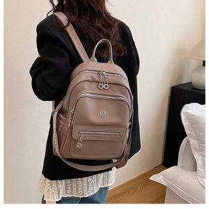 Detail of taupe PU leather backpack with lychee texture and woven straps worn by model