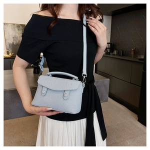 Detail of light blue denim fabric texture and double buckles on a small crossbody bag
