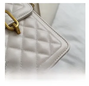 Close-up of beige quilted leather crossbody bag showing fine stitching and gold hardware