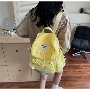 Dettaglio dello zaino in nylon giallo brillante con tasca strutturata ed etichetta tessuta