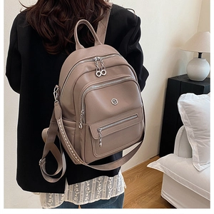 Brown lychee leather backpack with woven straps shown on model in a cozy home setting