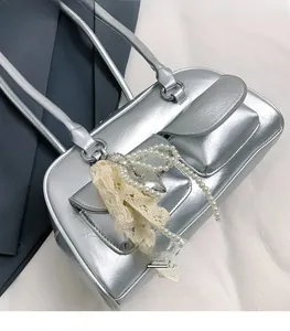 Détail d'un sac à main argenté métallisé avec deux poches à rabat et breloque cœur en perles