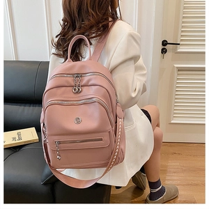 Detail of pink pebbled leather backpack with woven strap and silver zipper accents