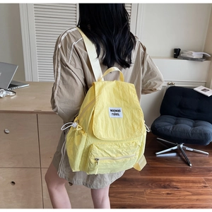 Vista posteriore della modella con zaino in nylon giallo brillante e spalline bianche