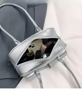 Détail de l'intérieur spacieux du sac à bandoulière argenté avec divers accessoires