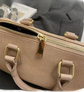 Detail of smooth gold zipper and woven texture on beige crossbody handbag