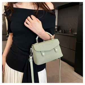 Detail of light green woven texture handbag with leather handles and detachable shoulder strap