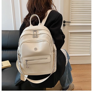 Detail of off-white lychee grain leather backpack with silver zippers and woven strap