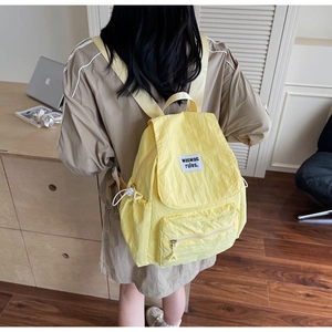 Detail of yellow nylon backpack featuring zipper front pocket and waswac rules logo tag