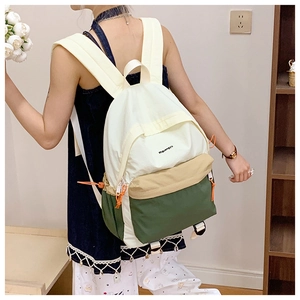 Detail view of lightweight tricolor waterproof hiking backpack worn by a model in interior