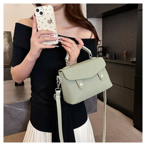 Detail of mint green small crossbody bag with twill texture and dual handle straps