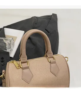 Detail of Boston-style handbag showing woven beige fabric and light brown faux leather handles