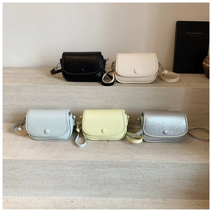 Group of small pebbled leather crossbody bags in five colors on stone steps display