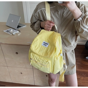 Dettaglio dello zaino in nylon giallo con coulisse e tasca frontale con cerniera