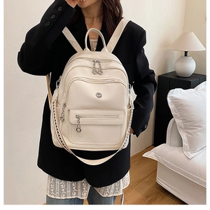 Close-up of cream faux leather backpack with woven straps and metal logo detail