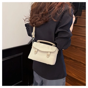 Detail view of beige woven crossbody bag with silver hardware on a female model
