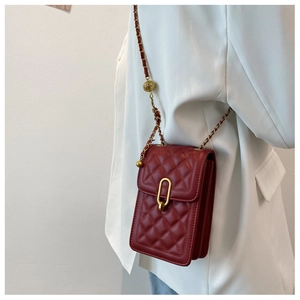 Detailed view of red quilted leather crossbody bag with gold chain and metal sphere