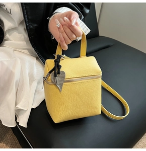 Dettaglio di una borsa a scatola gialla con texture litchi e ciondolo a cuore