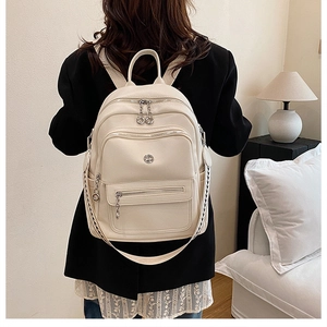 Detail of cream white leather backpack showing shoulder straps and multi-zipper pockets