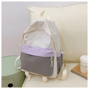 Detail of color-block waterproof nylon backpack with side pockets in a lifestyle setting