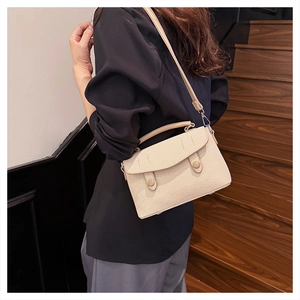 Detail shot of the textured beige crossbody bag with cylindrical snap buttons and strap