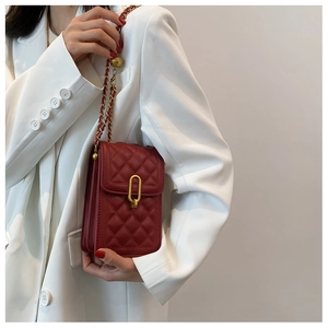 Detail of red quilted crossbody bag with gold clasp and elegant chain shoulder strap