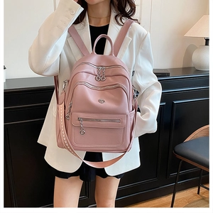 Detailed close-up of a pink textured PU leather backpack with silver zippers and woven strap