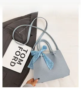 Détail du sac à main bleu clair en tissu texturé avec foulard à pois et bandoulière fine