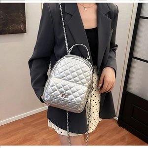 Detail eines silbernen gesteppten Mini-Rucksacks mit Metallkette an einem Model im Studio