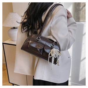Détail du sac baguette en cuir marron foncé avec dentelle et glands en perles élégants