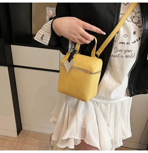 Dettaglio borsa gialla in pelle litchi con ciondolo a cuore e zip in argento lucido