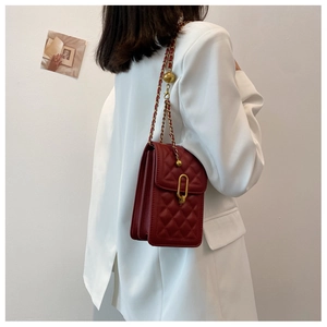 Detail of red quilted crossbody bag with adjustable golden ball chain and U-shaped lock