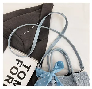 Gros plan d'un sac seau tissé bleu clair avec un élégant foulard en soie à pois