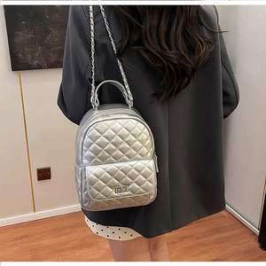Silberner gesteppter Mini-Rucksack mit Kettenriemen auf einem grauen Blazer